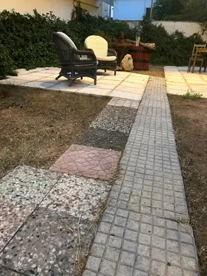 a stone walkway with two benches in a yard at Paola’s Apartment Near Athens Airport in Spáta