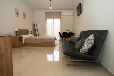 a living room with a couch and a bed at Anesis Airport rooms 204 in Koropíon