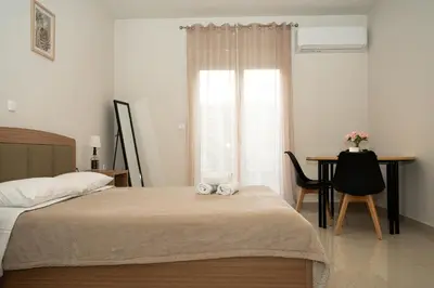 a bedroom with a bed and a desk and a window at Anesis Airport rooms 204 in Koropíon
