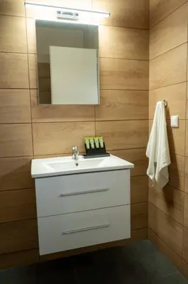 a bathroom with a white sink and a mirror at Anesis Airport rooms 204 in Koropíon