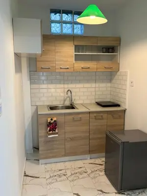 a kitchen with wooden cabinets and a sink at Paola’s apartments near Athens Airport in Spáta