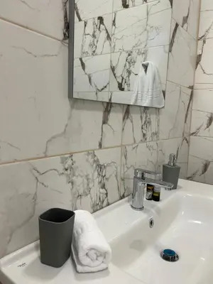 a white bathroom with a sink and a mirror at Paola’s apartments near Athens Airport in Spáta