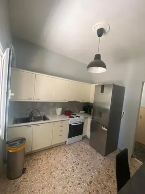 a kitchen with white cabinets and a silver refrigerator at Lovely flat Korydallos in Piraeus