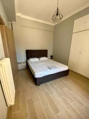a bedroom with a bed and a wooden floor at Cozy flat Korydallos in Piraeus