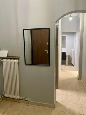 a hallway with a mirror on the wall and a hallway with a door at Cozy flat Korydallos in Piraeus