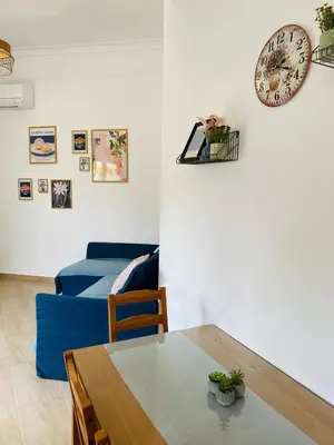 a living room with a table and a clock on the wall at Azure House in Athens