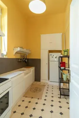a kitchen with yellow walls and a black and white floor at Casanova94 Guesthouse in Piraeus