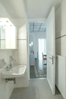 a white bathroom with a sink and a hallway at Casanova94 Guesthouse in Piraeus