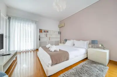 a white bedroom with a large bed and a television at The HostMaster Luminous Elite Estate in Athens