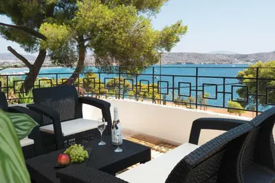 a patio with chairs and a table with a view of the water at Varkiza Sea Front Residence by First Class Properties in Vari