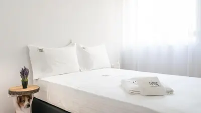 a bed with white sheets and a dog sitting on it at Varkiza Sea Front Residence by First Class Properties in Vari