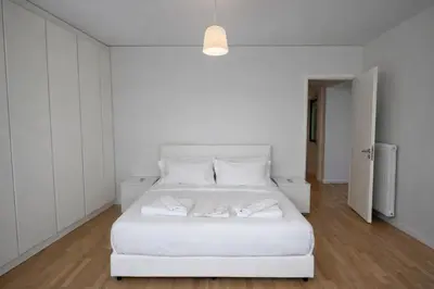 a white bedroom with a white bed with white pillows at Modern flat close to the beach-ground floor in Athens