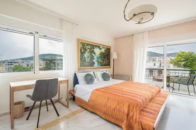 a bedroom with a bed and a desk and windows at Varkiza Riviera in Varkiza