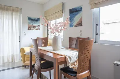 a dining room table with chairs and a vase with flowers at Varkiza Riviera in Varkiza