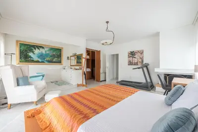 a white bedroom with a bed and a chair and a piano at Varkiza Riviera in Varkiza