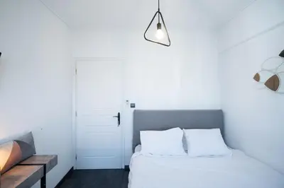 a white bedroom with a bed with white pillows at Duplex Penthouse with Sauna & Acropolis View in Athens