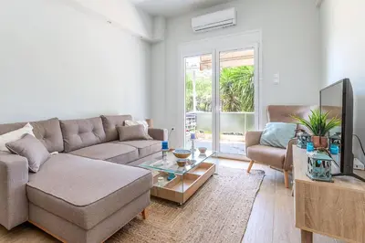 a living room with a couch and a tv at Cozy 2BD Beachfront Escape In The Heart Of Glyfada in Athens