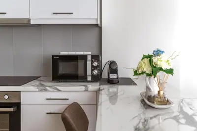 a kitchen with a microwave and a vase of flowers at Cozy 2BD Beachfront Escape In The Heart Of Glyfada in Athens