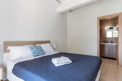 a bedroom with a large bed with a blue blanket at Cozy 2BD Beachfront Escape In The Heart Of Glyfada in Athens