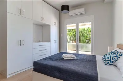 a white bedroom with a bed and a window at Cozy 2BD Beachfront Escape In The Heart Of Glyfada in Athens