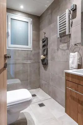 a bathroom with a toilet and a sink and a window at Cozy 2BD Beachfront Escape In The Heart Of Glyfada in Athens