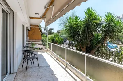a balcony with a table and chairs and palm trees at Cozy 2BD Beachfront Escape In The Heart Of Glyfada in Athens