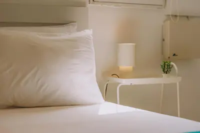 a white bed with a white pillow and a lamp at Top-Floor Studio in Glyfada Center with Sea View in Athens