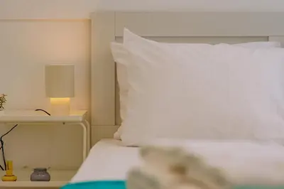 a bed with a white pillow and a table with a lamp at Top-Floor Studio in Glyfada Center with Sea View in Athens