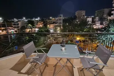 a white table and chairs on a balcony at night at Park View - PS4 in Piraeus