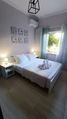 a bedroom with a white bed with a window at Katerina Holiday House in Anavissos