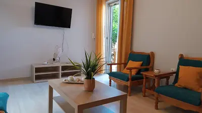 a living room with chairs and a table and a tv at Katerina Holiday House in Anavissos