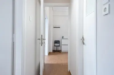 a hallway with a chair in a room with white walls at Comfortable Apartment In Athens in Athens