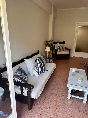 a living room with a couch and a table at Sea view apartment steps away from the Beach Anavyssos Palaia Fokaia in Áyios Yeóryios