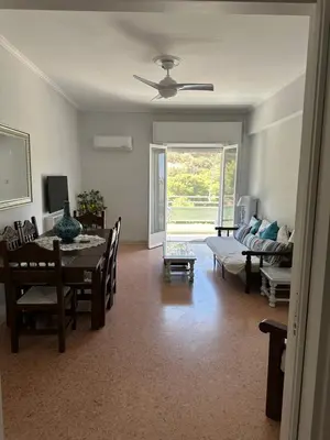 a living room with a table and a dining room at Sea view apartment steps away from the Beach Anavyssos Palaia Fokaia in Áyios Yeóryios
