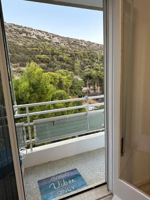 a sliding glass door with a view of a mountain at Sea view apartment steps away from the Beach Anavyssos Palaia Fokaia in Áyios Yeóryios