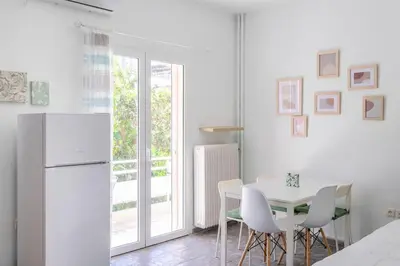 a white kitchen with a table and a refrigerator at Private Voula Beach Suite in Athens