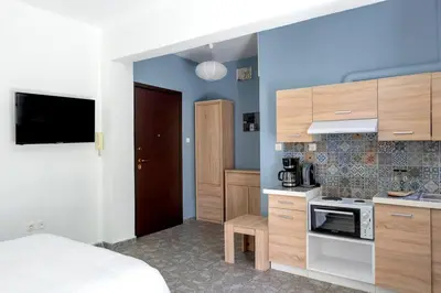 a bedroom with a bed and a kitchen with a stove at Private Voula Beach Suite in Athens