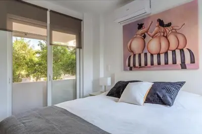 a bedroom with a bed and a painting on the wall at Hidden Gem: 2BR Artistic Retreat in Glyfada Center in Athens