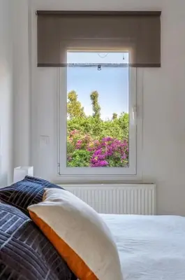 a bedroom with a window with a bed and flowers at Hidden Gem: 2BR Artistic Retreat in Glyfada Center in Athens
