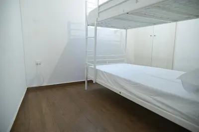 a white bedroom with a bunk bed and a wooden floor at Sea Front Sophia Porto Rafti in Porto Rafti