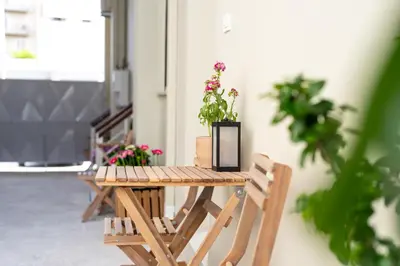 a wooden table with flowers in a black vase on it at Valhalla - Brand New Airport Apt. in Spáta