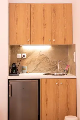 a kitchen with wooden cabinets and a stainless steel refrigerator at Valhalla - Brand New Airport Apt. in Spáta