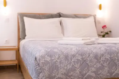 a bed with white pillows and a gray and white comforter at Valhalla - Brand New Airport Apt. in Spáta