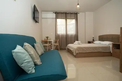 a living room with a couch and a bed at Anesis Airport rooms 306 in Koropíon
