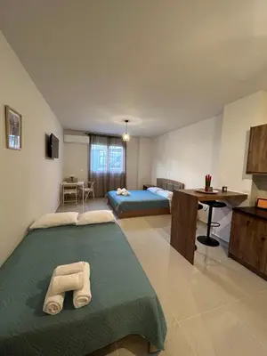 a bedroom with two beds and a desk and a table at Anesis Airport rooms 306 in Koropíon