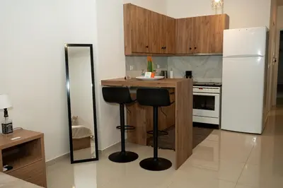 a kitchen with a counter with two stools and a refrigerator at Anesis Airport rooms 306 in Koropíon