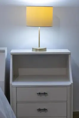 a white bedside table with a lamp on it at Piraiki Coastal Accommodation in Piraeus