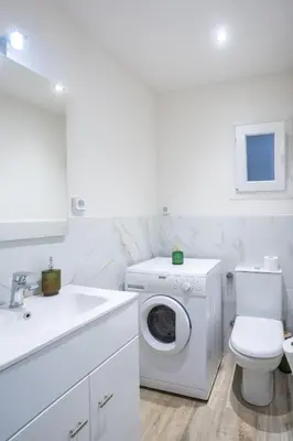 a white bathroom with a washing machine and a sink at Piraiki Coastal Accommodation in Piraeus