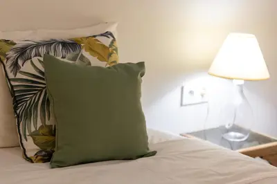 a green pillow sitting on a bed next to a lamp at Piraiki Coastal Accommodation in Piraeus