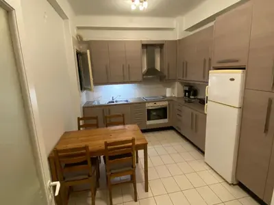 a kitchen with a wooden table and a white refrigerator at Διαμερίσμα με 1 κρεβατοκάμαρα και ένα σαλόνι in Athens